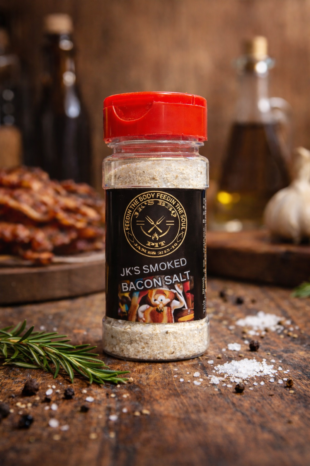 Bottle of smoked bacon salt on rustic wooden table with cooked bacon and garlic in background