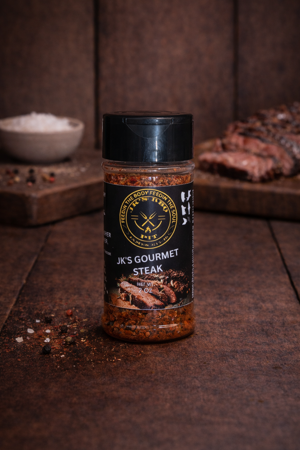 JK’s Gourmet Steak seasoning bottle on rustic wooden table with grilled steak
