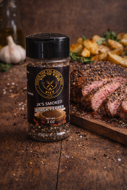BBQ smoked black pepper seasoning by JK's BBQ Pit with sliced steak and roasted potatoes on a rustic wooden serving board.