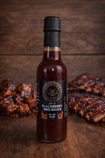 JK’s Blackberry BBQ Sauce bottle on rustic wooden background with glazed ribs and grilled chicken