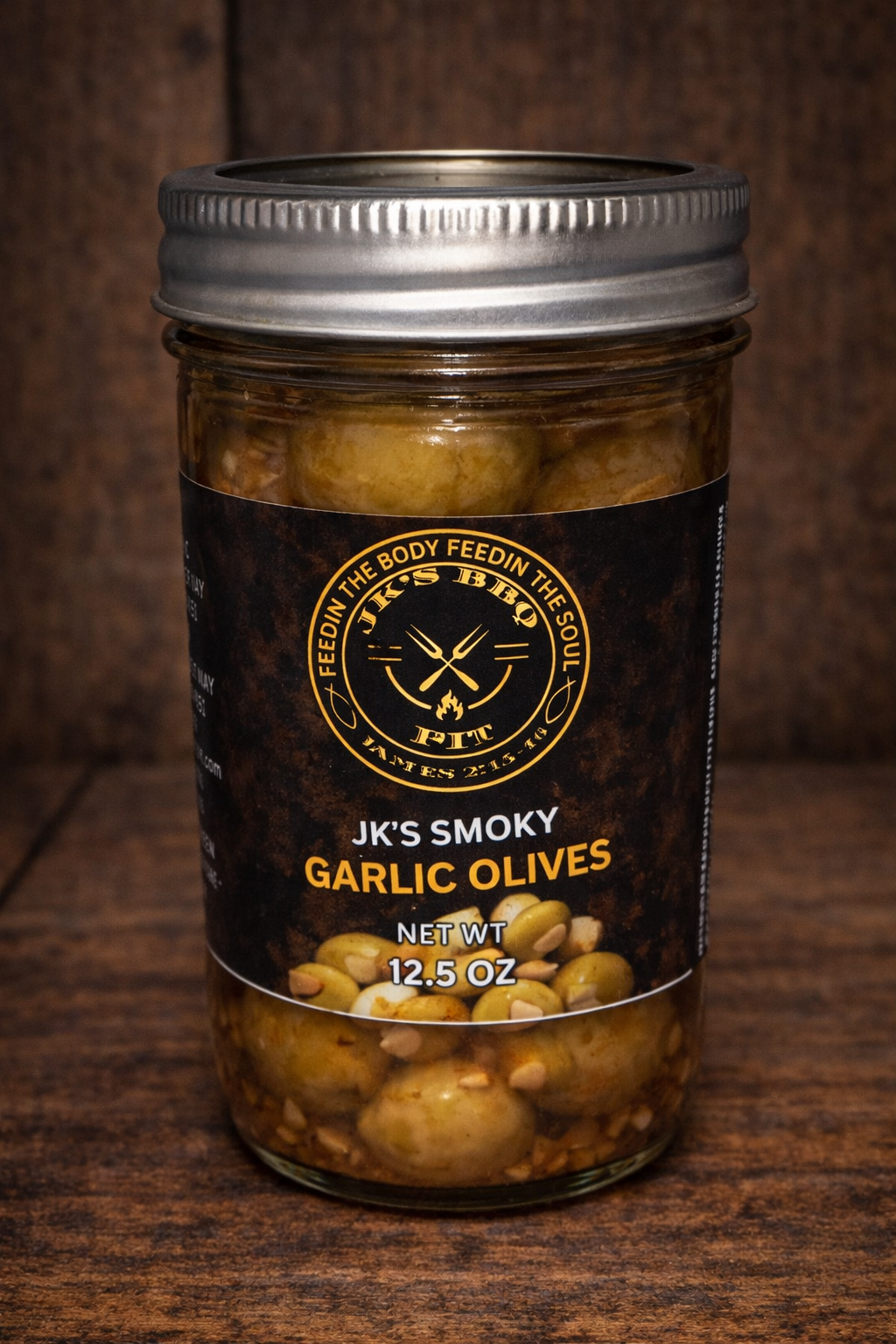 JK's BBQ Pit Smoky Garlic Olives in a 12.5 oz mason jar with black and gold label on a rustic wooden background