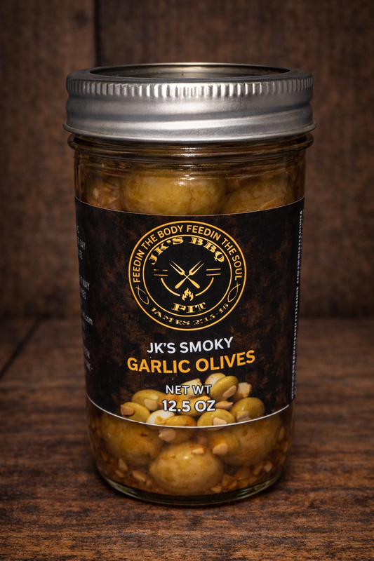 JK's BBQ Pit Smoky Garlic Olives in a 12.5 oz mason jar with black and gold label on a rustic wooden background