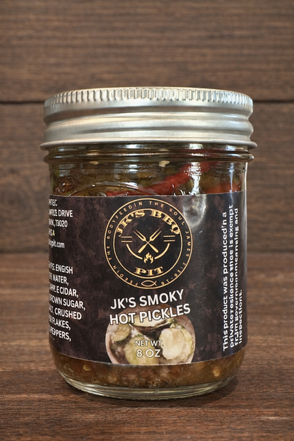 JK's BBQ Pit Smoky Hot Pickles 8 oz jar on rustic wooden background with sliced pickles and red peppers in smoky brine