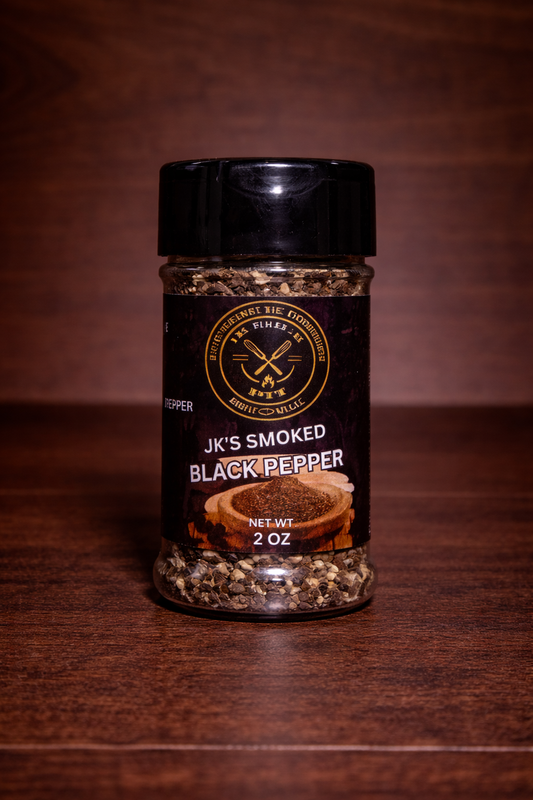 JK’s Smoked Black Pepper 2 oz bottle on wooden background with coarse cracked pepper visible in clear seasoning jar