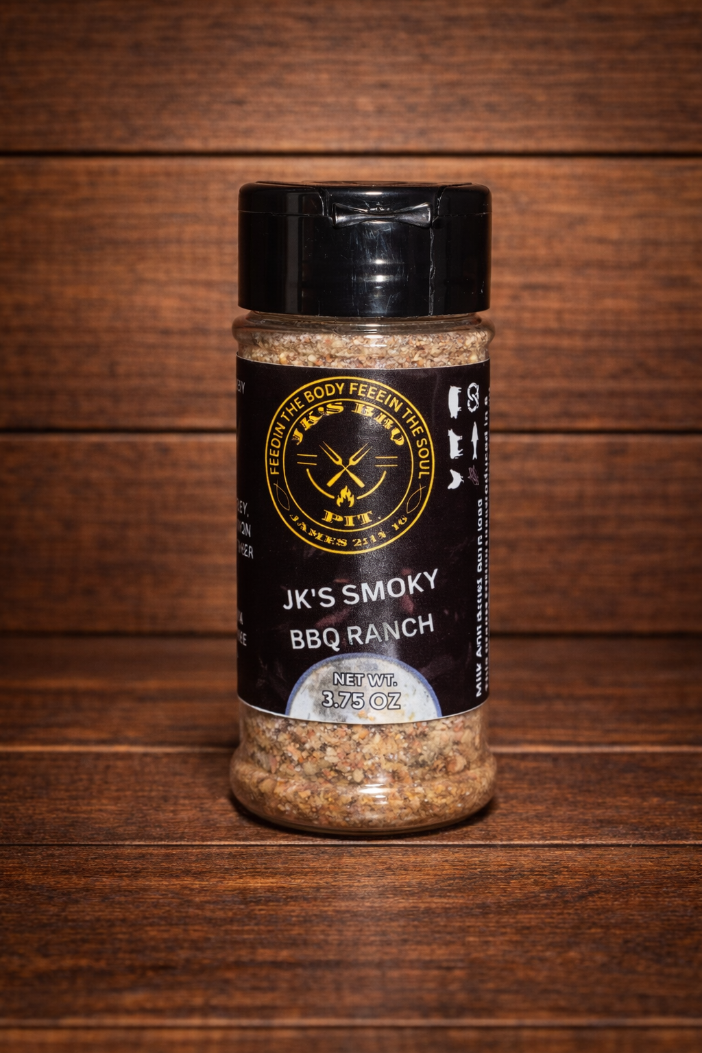 JK's Smoky BBQ Ranch seasoning bottle on a rustic wooden table and wood wall background – smoky ranch BBQ rub for burgers, chicken, fries, and grilling